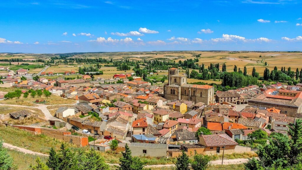 Vista panorámica de pueblo español con casas tradicionales y campo alrededor