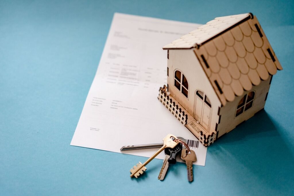 Casa de madera en miniatura con llaves y un contrato sobre una mesa