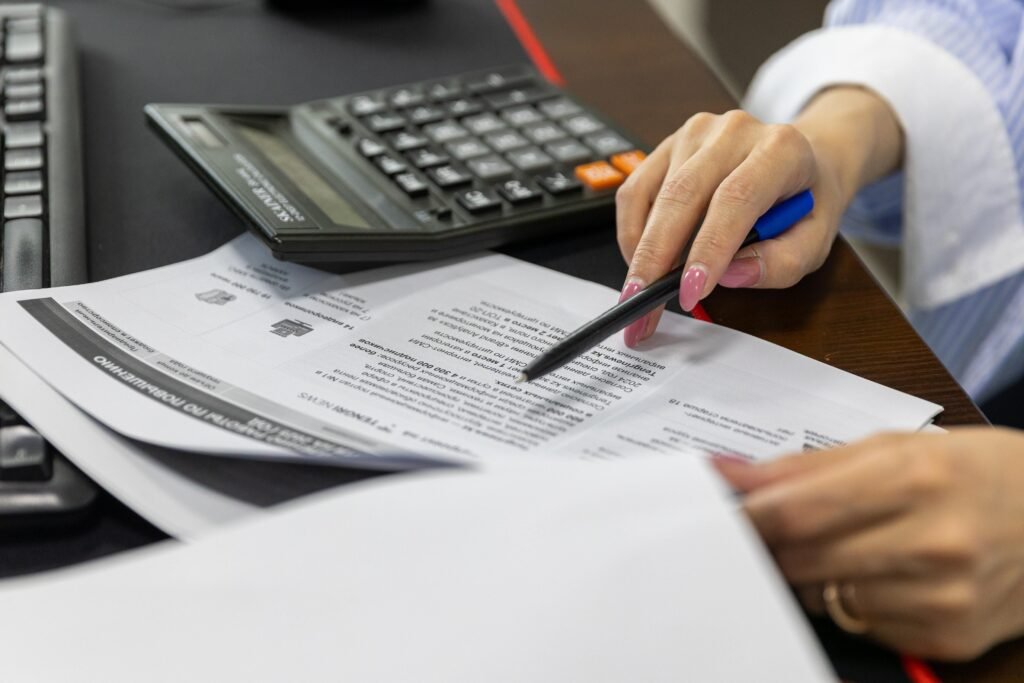 Persona revisando documentos con una calculadora para preparar la solicitud de una ayuda a la compra de vivienda